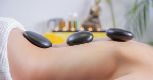 Heated stones on women's back for massage therapy.